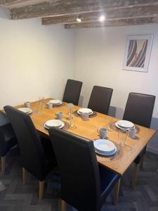 a wooden table with chairs and plates and wine glasses at Substantial 5 Bed Townhouse in Peterhead