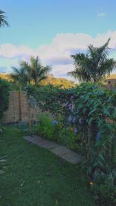 een tuin met paarse en blauwe bloemen en palmbomen bij Recanto Duas Rosas in Venda Nova do Imigrante