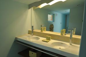 uma casa de banho com 2 lavatórios e um espelho grande em Le Pavillon du Lac em La Brede