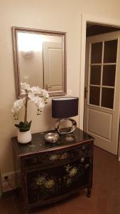 una mesa con un espejo y un jarrón con flores. en Green Field Lodge, en Lingolsheim