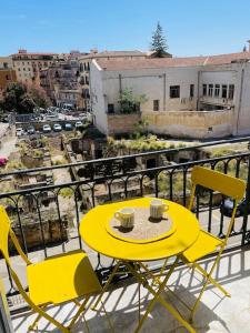 una mesa amarilla y sillas en el balcón en Monkey house Appartamento in centro storico, en Palermo