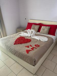 ein Bett mit roten Rosen und Handtüchern darauf in der Unterkunft Affittacamere" SANTA LUCIA" in Roccarainola