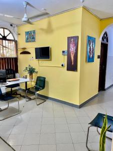 una oficina con una pared amarilla con mesa y sillas en Kelele Square en Zanzíbar