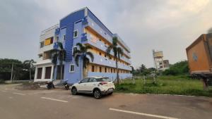 um carro branco estacionado em frente a um edifício azul em Vikistays em Chennai