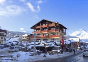 un gran edificio en una calle con nieve. en Les Aiguilles De Warens en Combloux