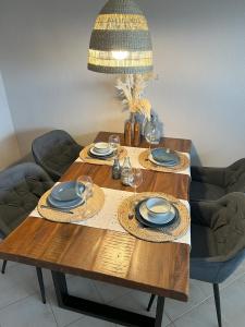 una mesa de madera con platos y gafas y una lámpara de araña en Ferienwohnung Dock 19 in Büsum, en Büsum