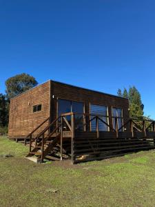 une petite cabane en bois avec une grande terrasse dans un champ dans l'établissement Cabaña en Pupuya Navidad, à Navidad