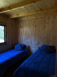 2 camas en una habitación con paredes de madera en Cabaña en Pupuya Navidad, en Navidad