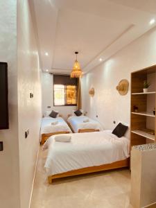 1 dormitorio con 2 camas y lámpara de araña en WOW beach house, en Imsouane