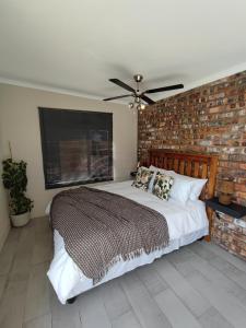 a bedroom with a large bed with a brick wall at Blue Sky Retreat in Vredenburg