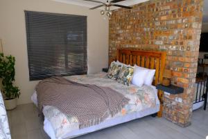 a bed in a room with a brick wall at Blue Sky Retreat in Vredenburg