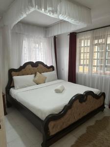 een slaapkamer met een groot bed met witte lakens bij Arlshy furnished apartments in Kisumu