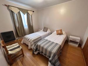 a bedroom with two beds and a chair and a window at Tierra de Canoeros in Ushuaia