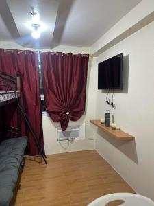 sala de estar con cortina roja y TV en SEAWIND TOWER 6 CONDOMINIUM en Dávao