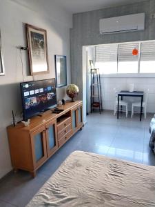 una sala de estar con TV en un centro de entretenimiento de madera en Cozy Studio Apartment in Haifa, en Haifa