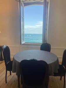 Le Royal XIX Dinard vue mer luxe في دينارد: غرفة طعام مع طاولة وإطلالة على المحيط