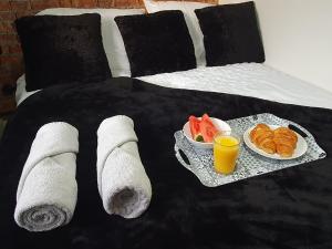 a bed with two plates of food and a tray of fruit at Little House On The Hill Conisbrough in Conisbrough