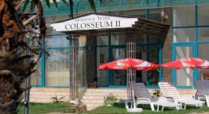 a group of chairs and umbrellas in front of a building at Colosseum 2 Aparthotel in Sunny Beach