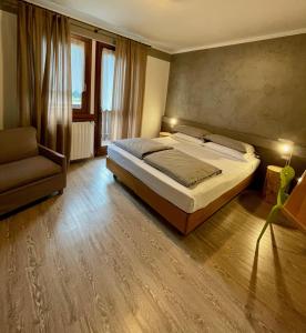 a bedroom with a large bed and a chair at Hotel Garni Sorriso in Ponte di Legno