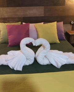 Dos cisnes de toalla haciendo un corazón en una cama en Casa Apartamento Rural U Penafrol, en Eljas