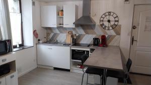 uma cozinha com uma mesa e um relógio na parede em Appartement climatisé avec vue sur les Remparts, centre de Rocroi, parking privatif et garage vélos em Rocroi
