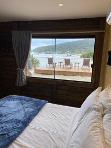 a bedroom with a large window with a view of the water at Pousada Kainoa in Ilha do Mel