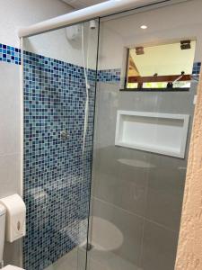 uma cabina de duche em vidro numa casa de banho com azulejos azuis em Pousada Kainoa na Ilha do Mel