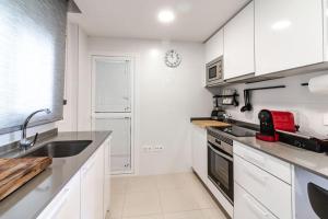 una cocina con armarios blancos y fregadero en Your Retreat Near Puerto Banús, en Marbella