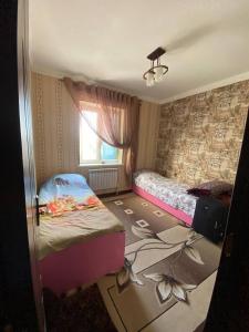 ein kleines Schlafzimmer mit 2 Betten und einem Fenster in der Unterkunft Апартаменть in Jizzax