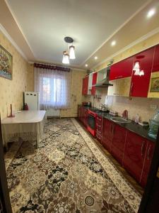 eine Küche mit roten Schränken und einem Tisch darin in der Unterkunft Апартаменть in Jizzax