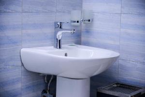 a white sink in a bathroom with blue tiles at Entebbes Trendy 3 Bedroom Suite in Namulanda