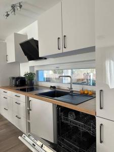 a white kitchen with a sink and a dishwasher at Family Apart nähe Nürnberg in Schwaig bei Nürnberg