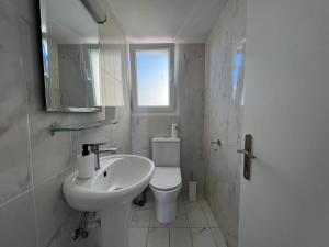 a white bathroom with a sink and a toilet at Sunny Rooms in Limassol