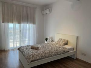 a white bedroom with a bed and a window at Sunny Rooms in Limassol