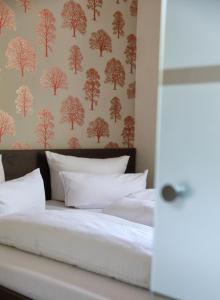 un letto con lenzuola bianche e carta da parati con alberi di Kulturhotel Kaiserhof a Bad Liebenstein