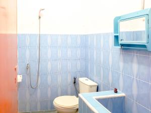 a blue tiled bathroom with a toilet and a window at Raffiel Nias in Lagudri