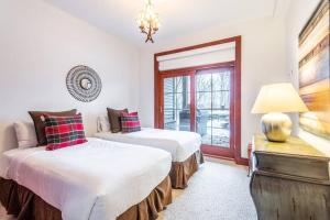 two beds in a room with a window at Ski In/Ski Out Luxury Tremblant Chalet in Mont-Tremblant