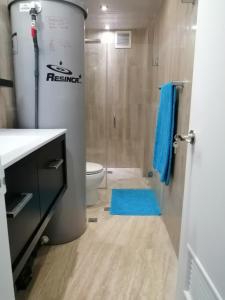 a bathroom with a toilet and a blue rug at Apartamento Deluxe Isla Margarita - Costa Azul in Porlamar