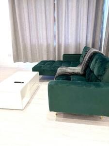 a living room with a green couch and a chair at Ace Apartments in Barking