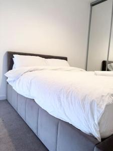 a bed with white sheets on it in a room at Ace Apartments in Barking
