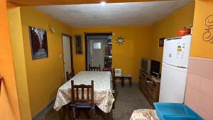 een keuken met een tafel en een witte koelkast bij Il Giardino de Santa in Santa Teresita +3 foto's
