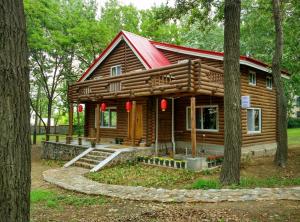 a log cabin with a red roof in the woods at 北戴河海边森林木屋别墅 in Qinhuangdao