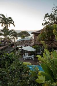 eine Terrasse mit einem weißen Tisch und einem Sonnenschirm in der Unterkunft Pousada Vila do Mar in Búzios