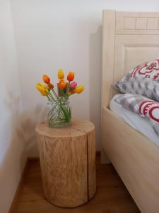 a vase of flowers sitting on a wooden table next to a bed at Apartmán Jezerné in Velké Karlovice