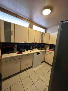 La cuisine est équipée de placards blancs et d'un réfrigérateur noir. dans l'établissement T4 au coeur des Alpes, à Bonneville