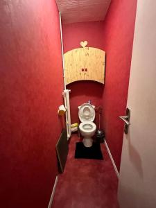 La salle de bains rouge est pourvue de toilettes dans un mur rouge. dans l'établissement T4 au coeur des Alpes, à Bonneville