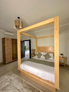 Babushka Boutique Hotel-Dahab في دهب: غرفة نوم مع سرير من المظلة الخشبية في غرفة
