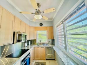 a kitchen with wooden cabinets and a ceiling fan at St Croix Bliss - Tranquil Retreat-Ocean Views-Island Breezes in Christiansted