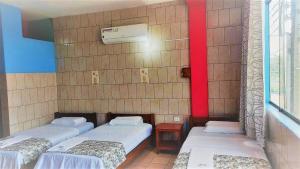 three beds in a room with red and blue walls at HOSTAL AKEMI in Yurimaguas