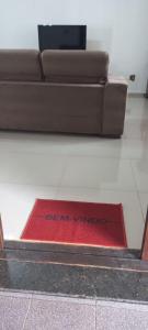 een rood tapijt op de vloer voor een bank bij Casa Temporada em Aparecida com vista para Basílica in Aparecida